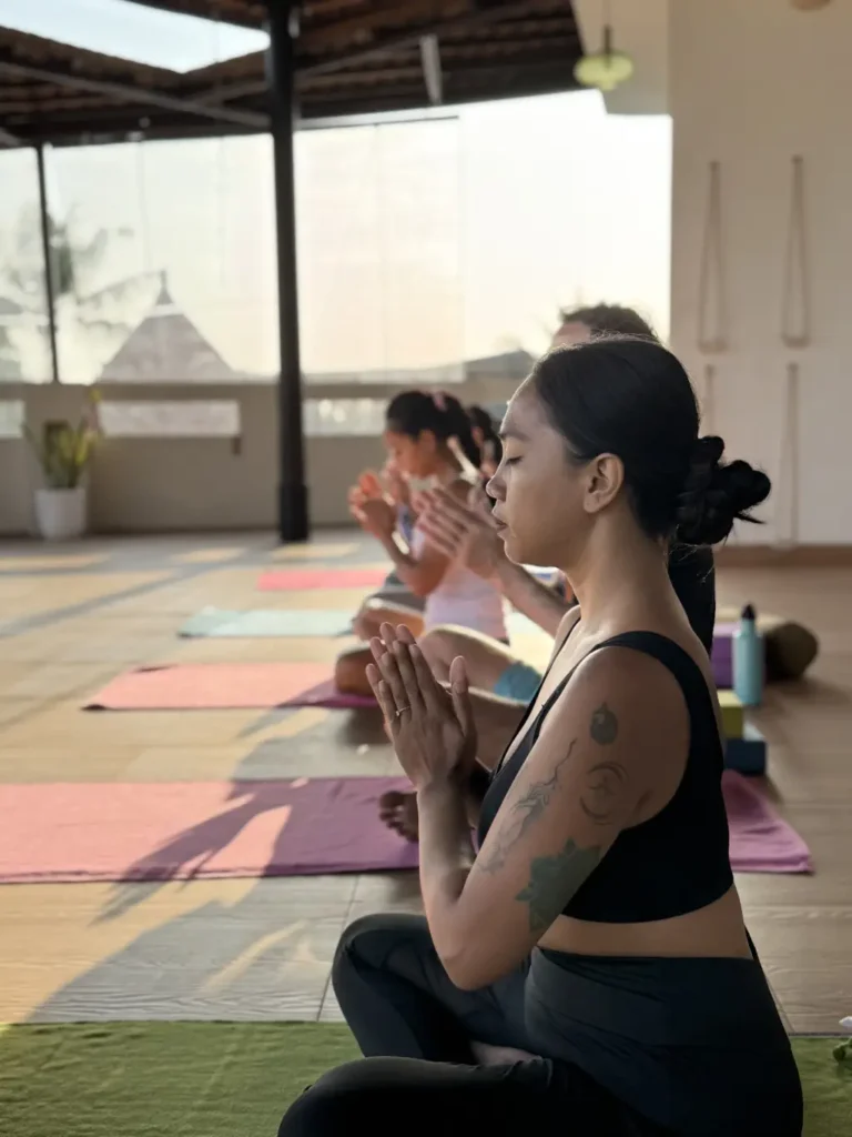 Women practicing mindfulness and meditation in an open-air yoga studio at sunrise