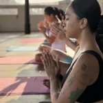 Women practicing mindfulness and meditation in an open-air yoga studio at sunrise
