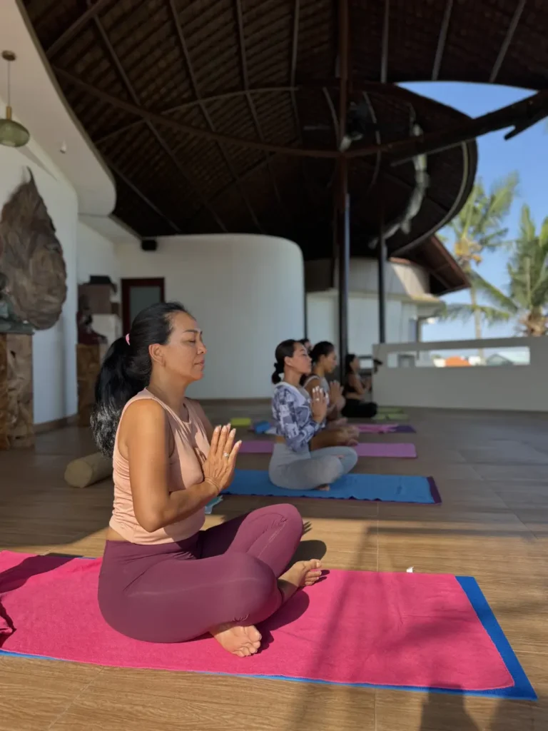 Group of women practicing meditation in a yoga class at an open-air studio
