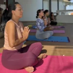 Group of women practicing meditation in a yoga class at an open-air studio