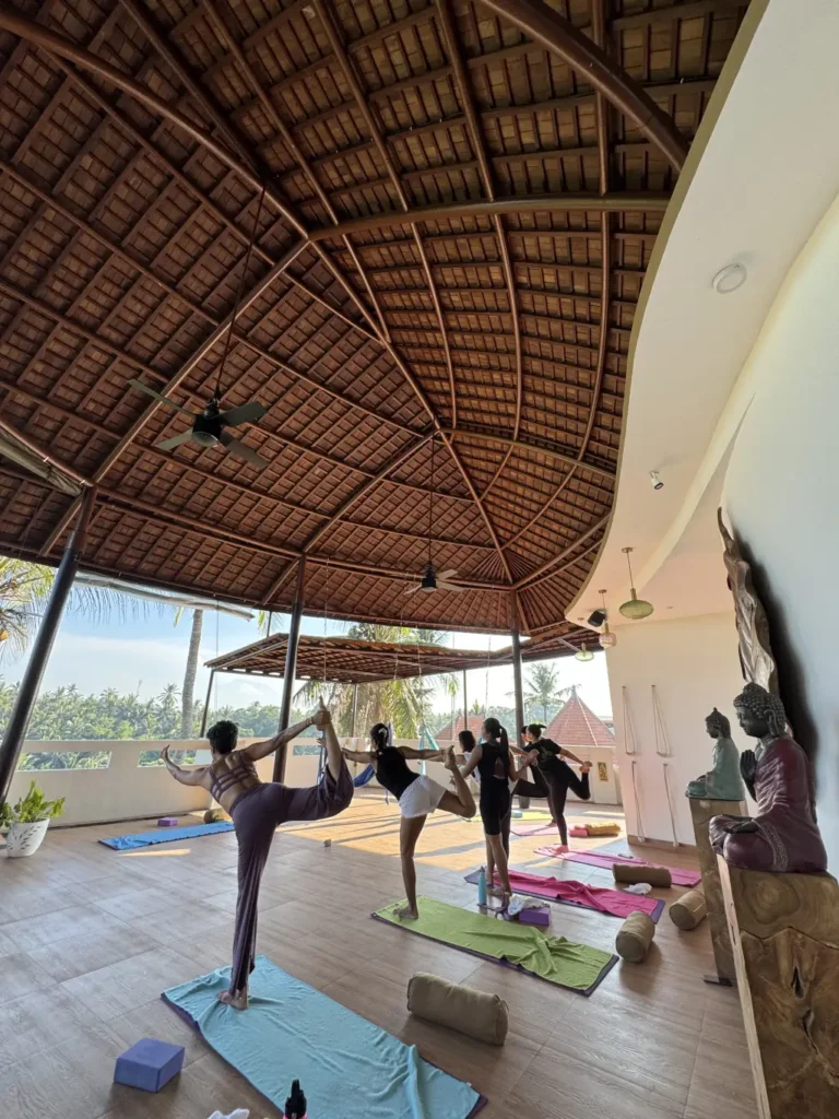 Group yoga class in an open-air tropical studio with scenic jungle views