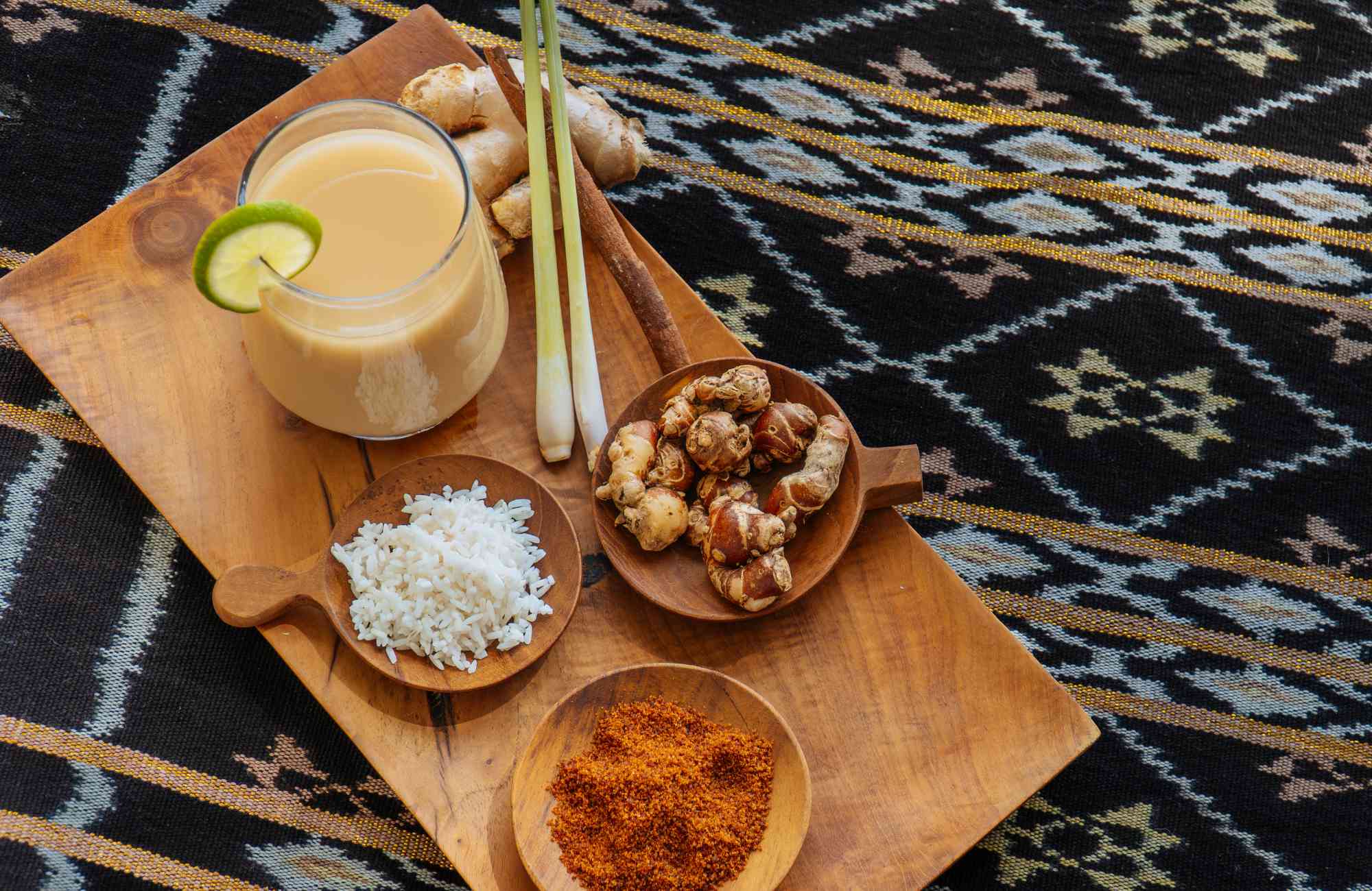 Various traditional herbs and spices used to make jamu, including turmeric, ginger, and tamarind, displayed in a rustic setting