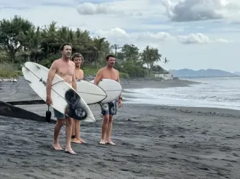 three guys bring surfing board in purnama beach