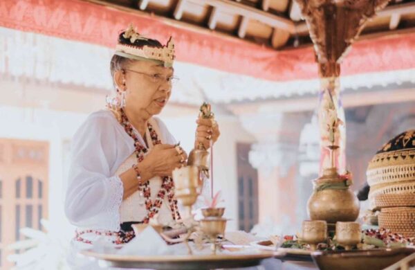 A Balinese healer conducting a shamanic healing session, surrounded by traditional tools and serene nature, to restore balance and energy