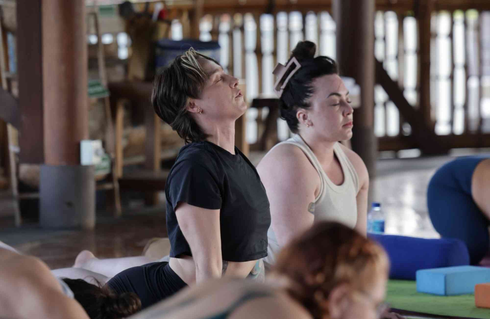 Participants engaging in yoga and meditation in a tranquil outdoor setting, surrounded by nature, promoting relaxation and mindfulness