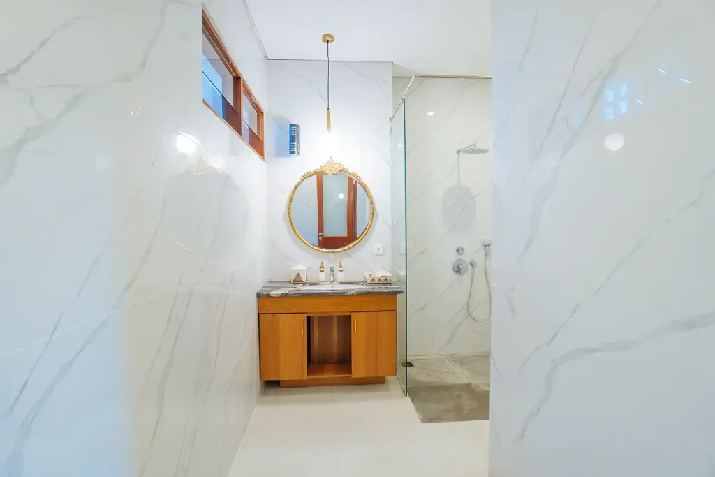 A modern bathroom at The Bodhi Leaf featuring a large mirror and elegant design for a refreshing experience