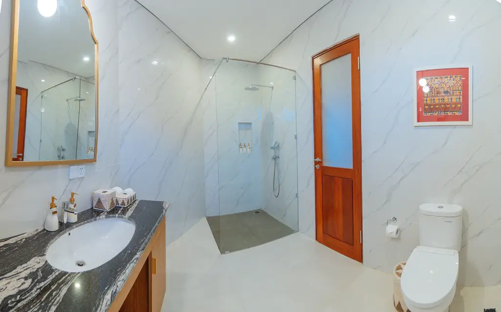 A clean, minimalist bathroom at The Bodhi Leaf with a shower and toilet, providing a comfortable and serene space