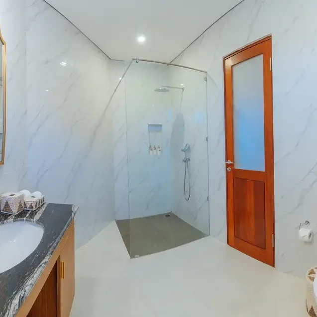 A clean, minimalist bathroom at The Bodhi Leaf with a shower and toilet, providing a comfortable and serene space