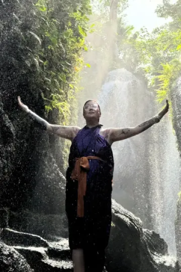 a girl standing with the hands up with waterfall view