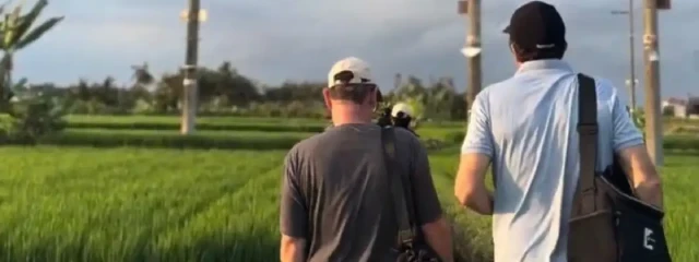 two man walking on the green rice field