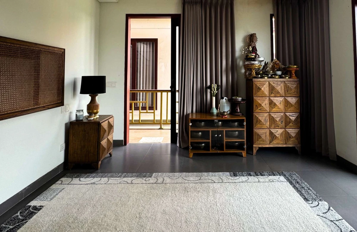 Bali-style bedroom with carved wood furniture, decorative altar, and balcony access