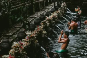 People performing a Balinese temple ritual, bathing under water spouts surrounded by traditional offerings